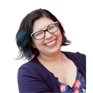 A smiling light-skinned mixed Latina with teal-streaked short dark hair, wearing black glasses and a floral top.