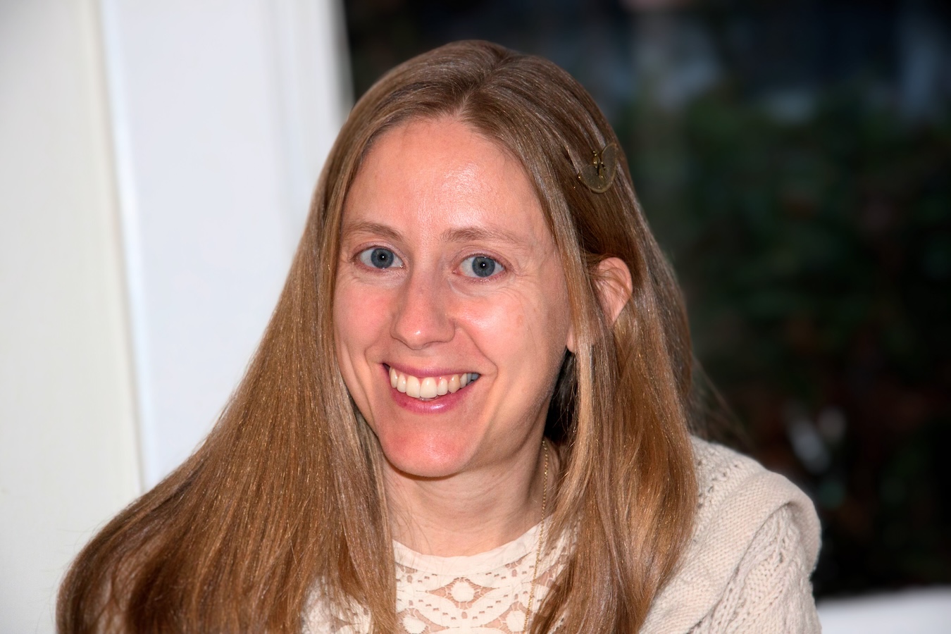 A smiling white woman with blue eyes and long, dark blonde hair. 